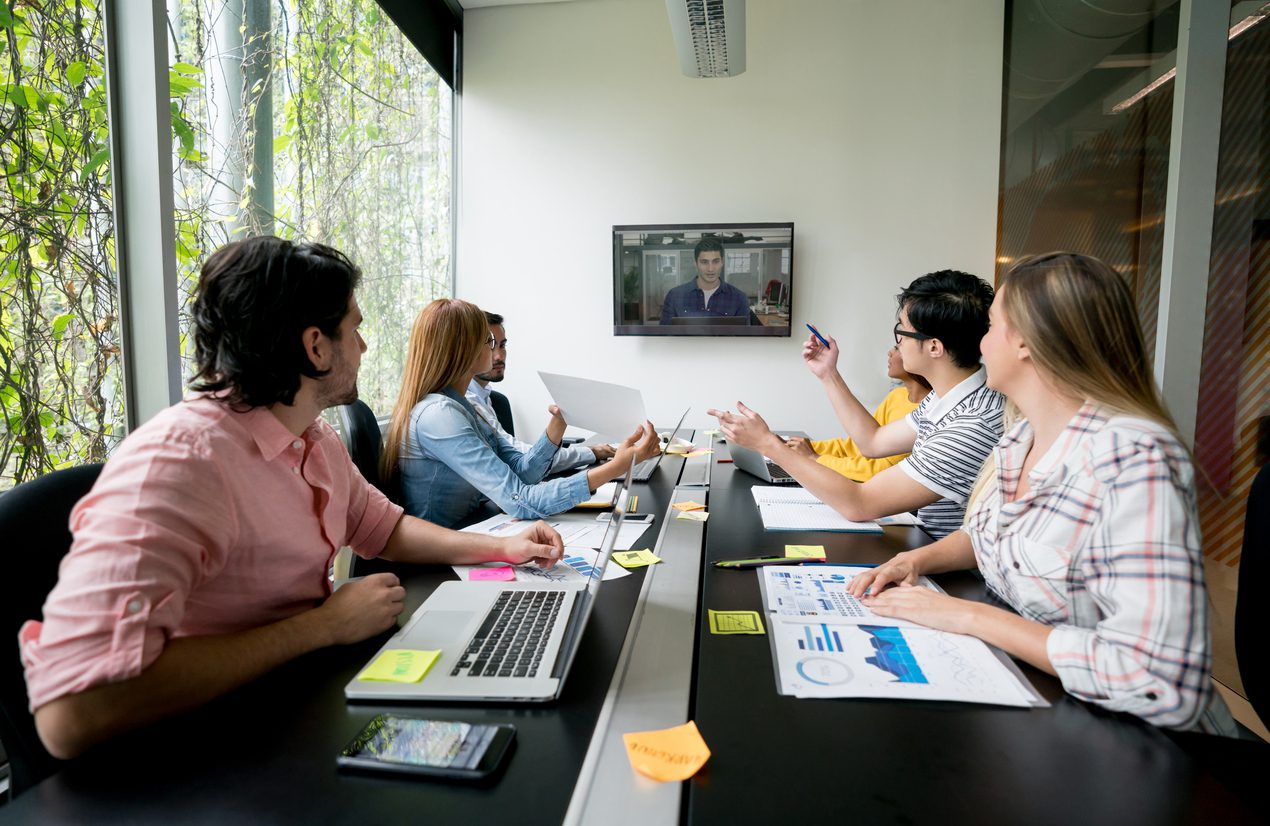 Group of people in a meeting at a creative office making a video conference and looking at the screen using Microsoft Teams.
